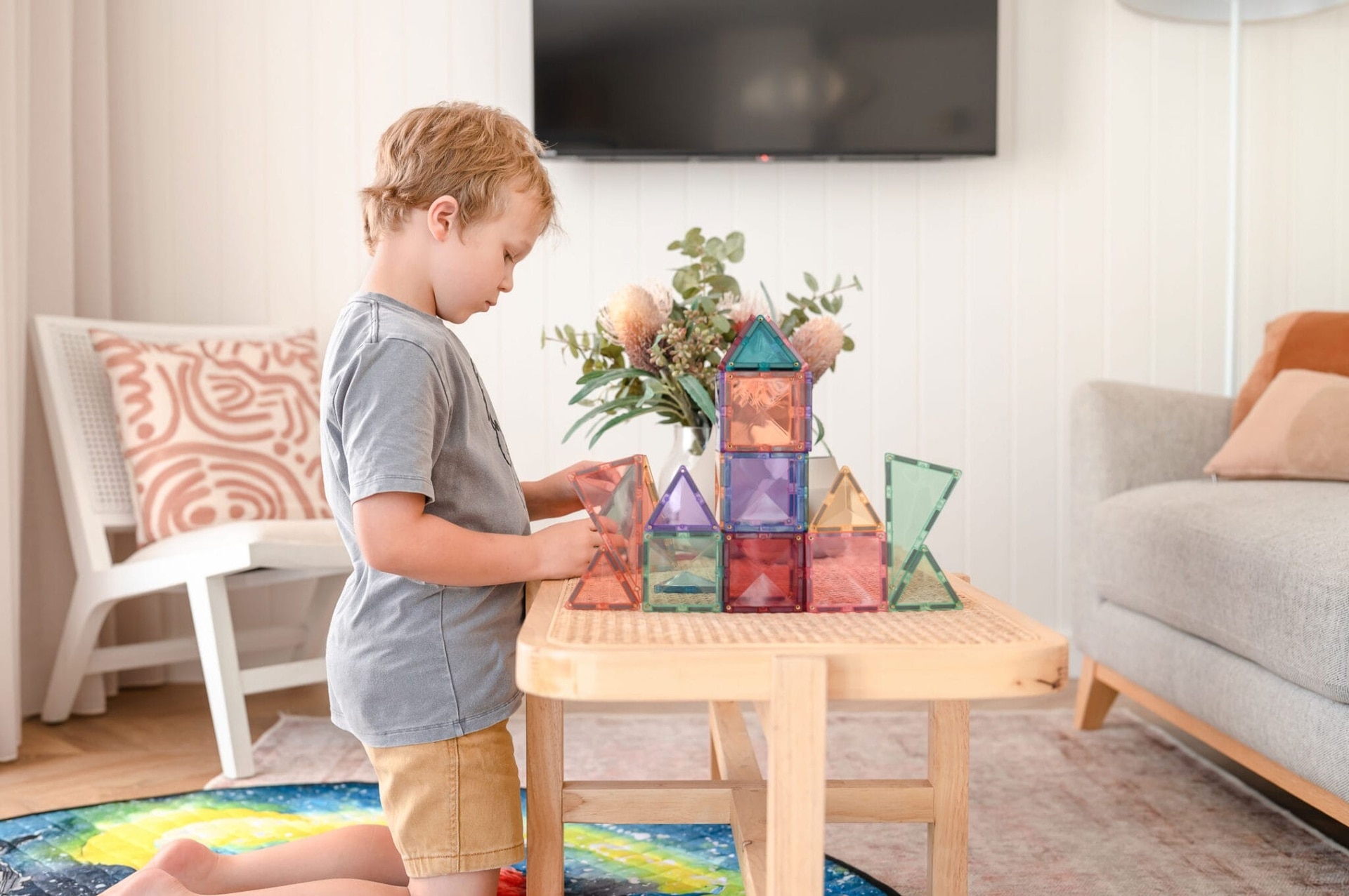 Un copil construiește un turn din setul de construcție magnetic pastel Connetix